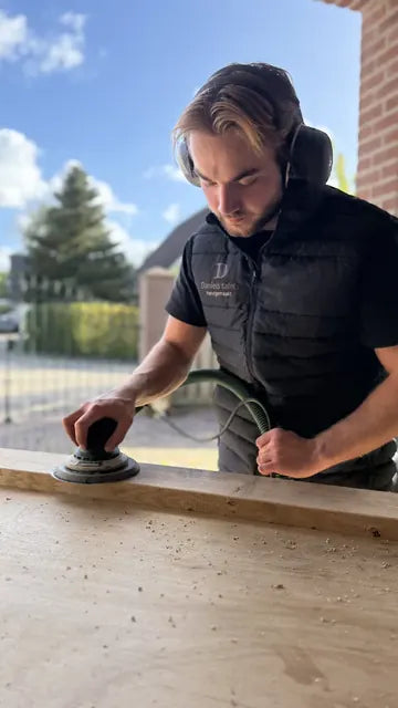 Rick schuurt hout aan zijn werkbank.